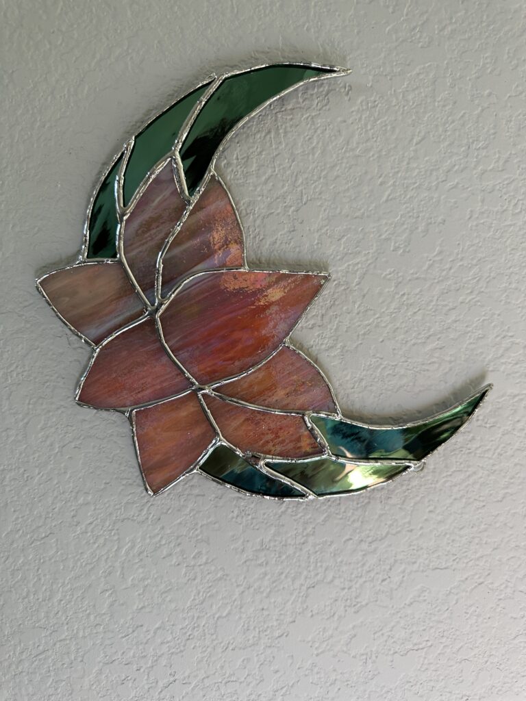 Green mirror glass forming a crescent moon and pink iridescent glass in the shape of a lotus in the center.