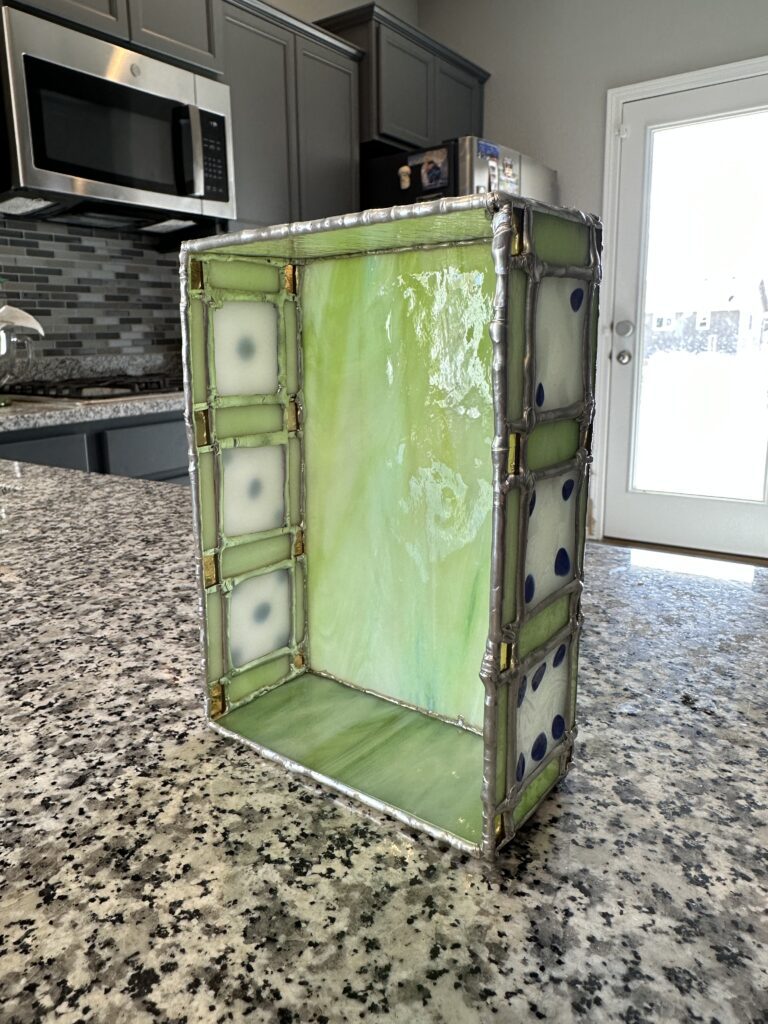 Light green tray standing on its end. You can see 3 dice faces on either side.