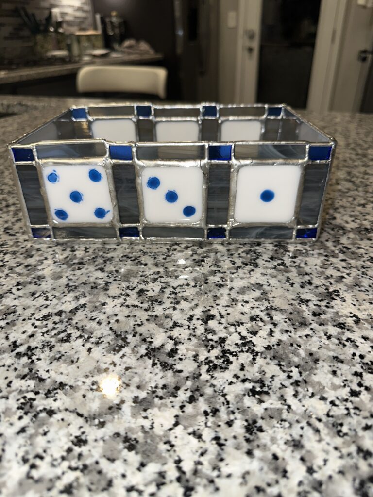 Gray dice tray with 3 die faces on one side facing the camera.