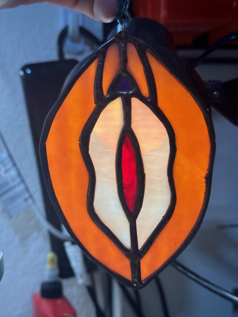 Stained glass yoni with a dark orange outside, pink middle, and deep red center.