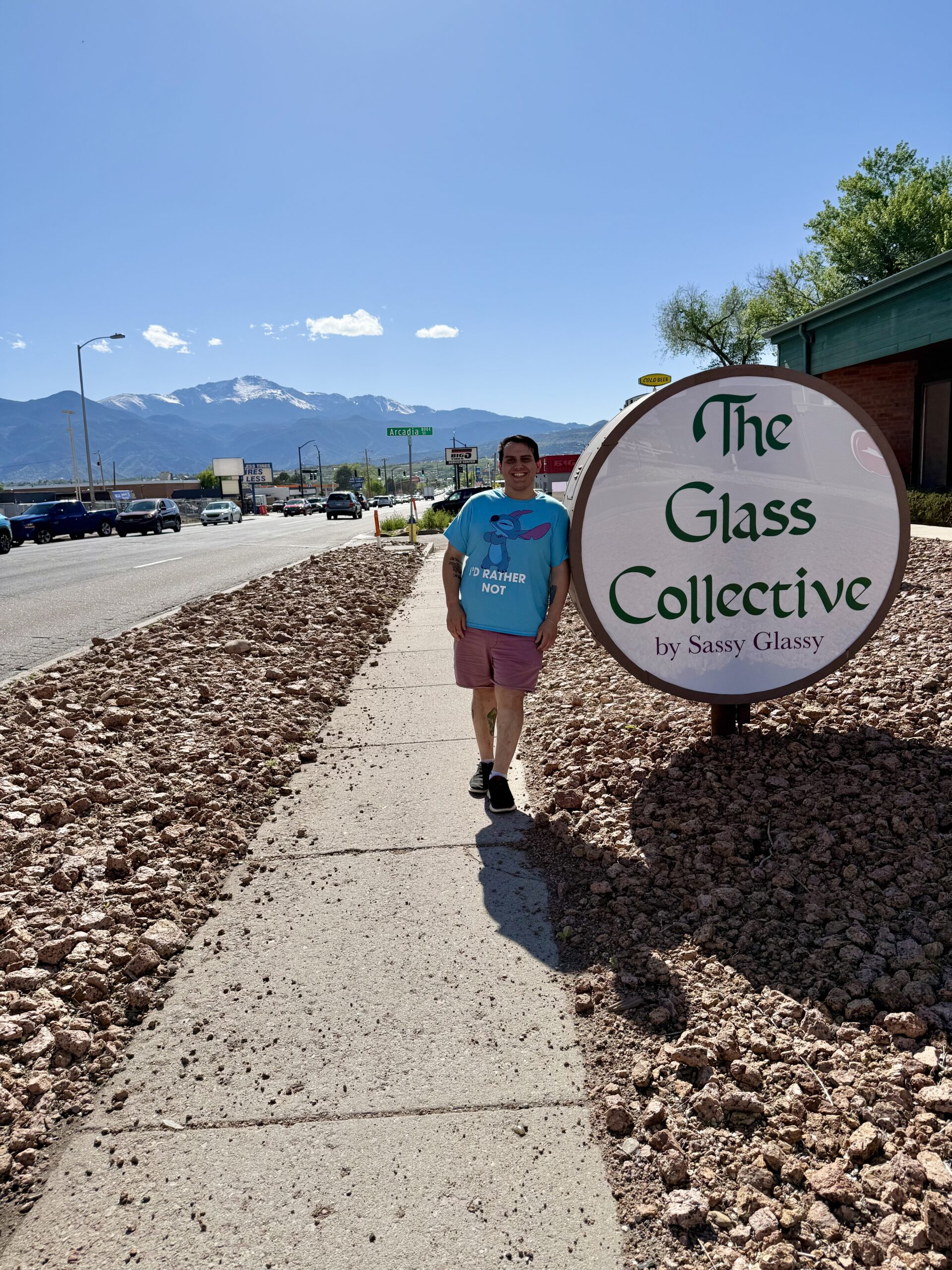 Eddie leaning against a round “The Glass Collective” sign.