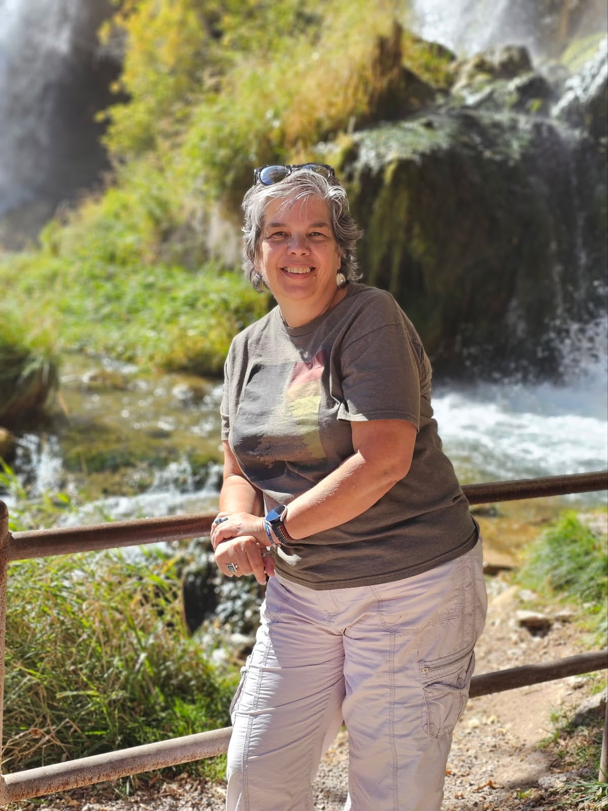 Photo of Cathy leaning against a railing in front of a river.