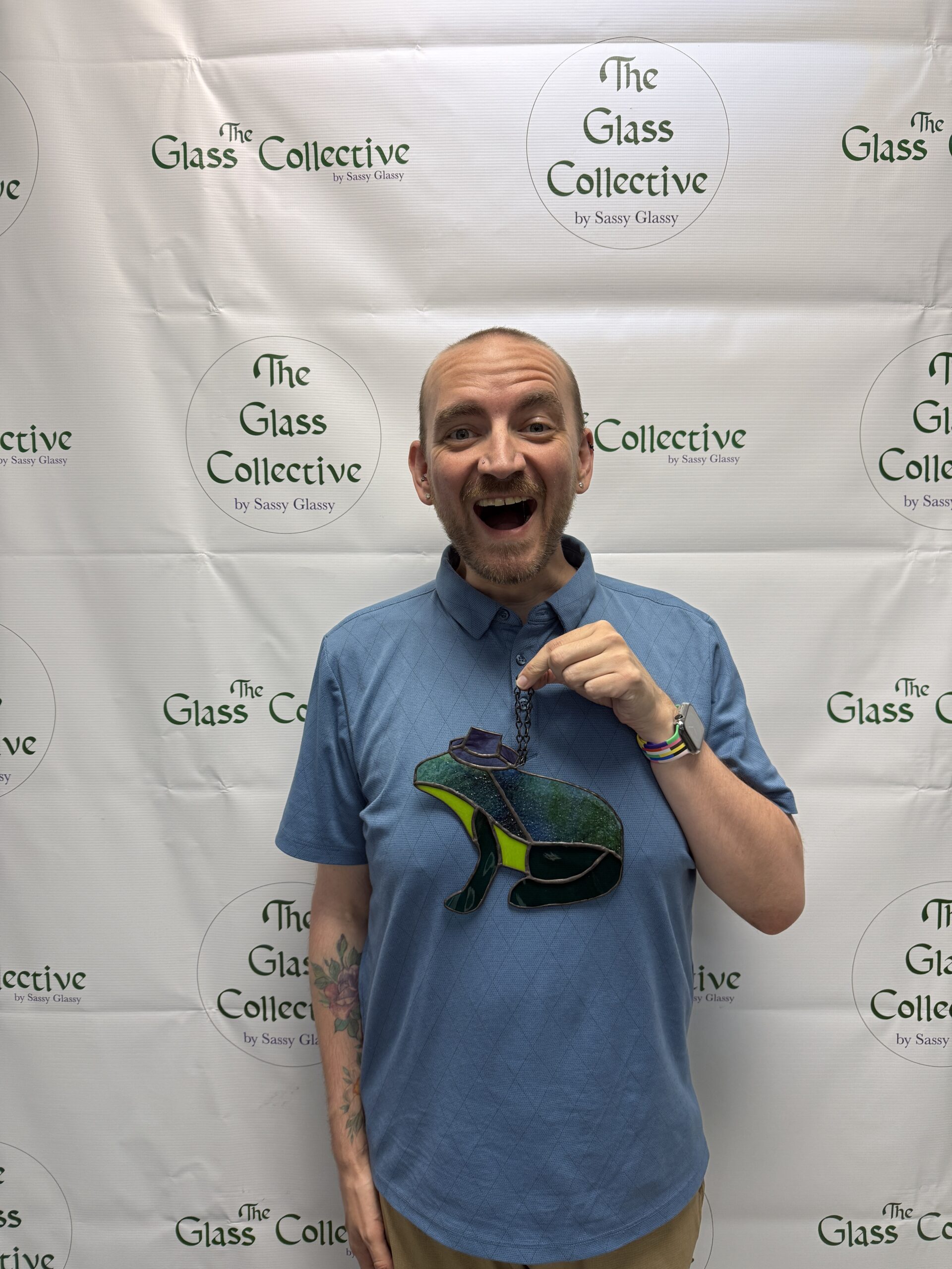 Image of David Peña holding a stained glass frog with a cowboy hat up.