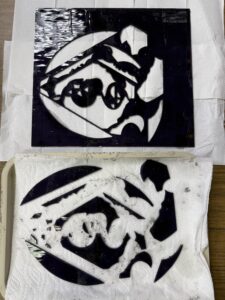 A sheet of glass with shapes cut out. Those cut shapes are on a tray next to the sheet.